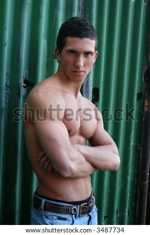 Shirtless muscular male model in front of the green crimping metal wall