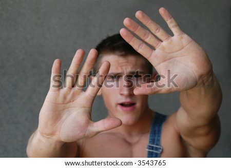 Young sexy man holding his palms out saying \'Stop\' or \'No\' - palms in focus