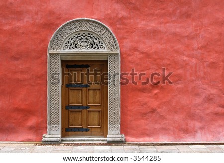 Carved medieval stone door in the red stucco wall in Zica Monastery, Serbia