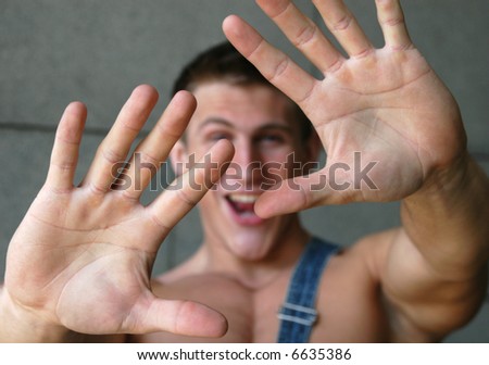 Young sexy man holding his palms out saying 'Stop' or 'No' - palms in focus