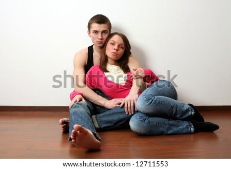 Loving couple sitting on the floor in an empty room