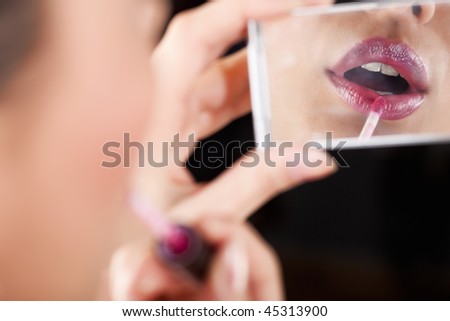 Closeup of lady applying lipstick. Selective focus, unrecognizable person.