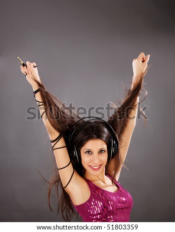 Cute teenage girl holding her hair up in the air with cable twisted around her arm and headphones on her head.