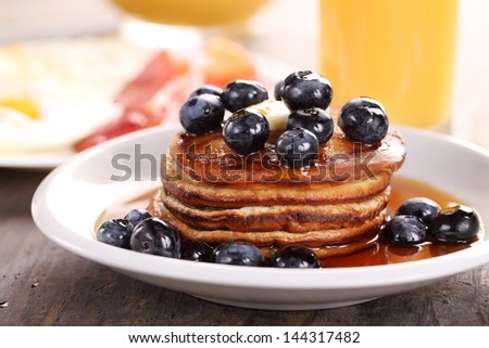 Close up of plate with pancakes, juice and eggs with bacon.