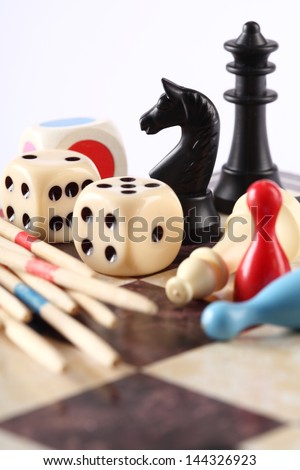 Detail of board games, pawns, chessmen, mikado and dices on chess board.