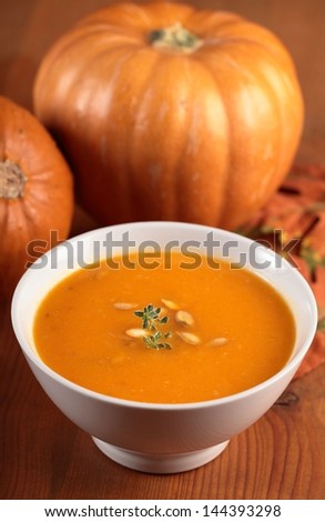 Bowl with pumpkin soup and pumpkins.