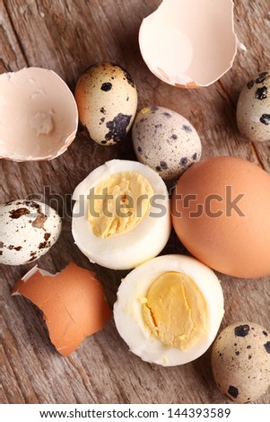 Close-up of hard boiled egg, egg shells and quail eggs.