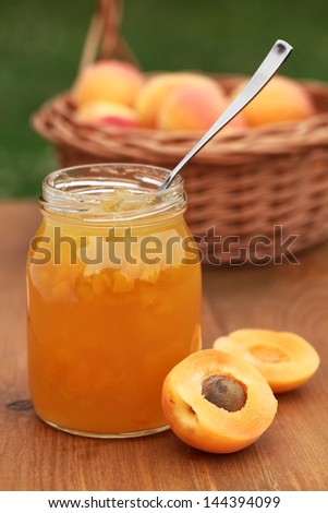 Glass with apricot jam and fresh apricots in basket
