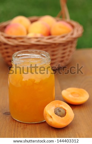 Glass with apricot jam and fresh apricots in basket