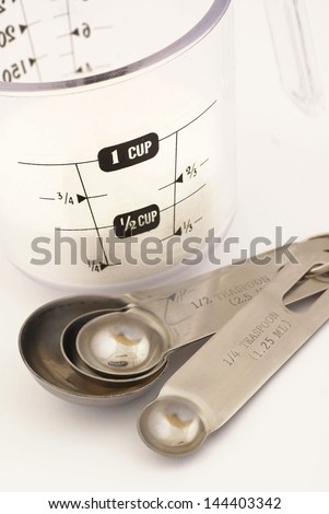 Measuring cup with sugar and measuring spoons on white background