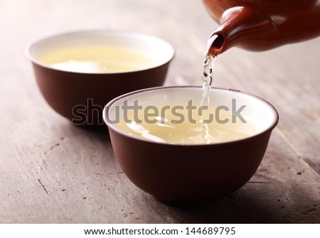Close-up of tea pot ant tea pouring into bowl.