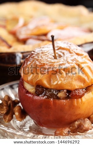 Baked stuffed apple on plate and detail of cake tin with apple pie