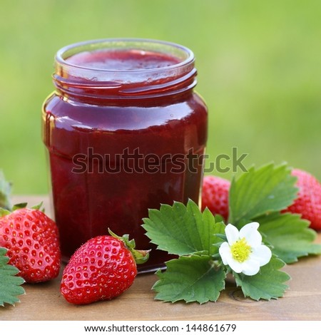 Glass with strawberry jam, strawberries and strawberry leaves and flower