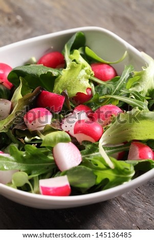 Bowl with various lettuce leaves and radishes.