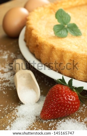 Cake, eggs, sugar and strawberry - baked cake before decorating, focus on strawberry