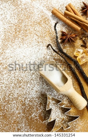 Anise star, cinnamon sticks, cloves, vanilla beans, brown and white sugar and cookie cutters on sugar background.