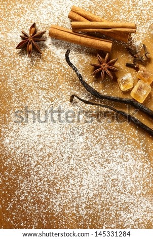 Anise stars, cinnamon sticks, vanilla beans and brown sugar on sugar background.