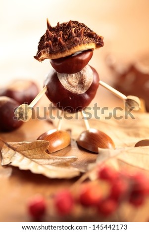 Chestnut and acorn figurine on wooden table. Selective focus, shallow DOF.