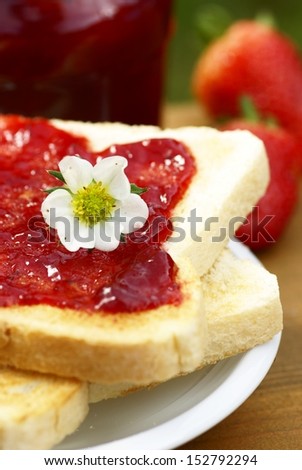 Close-up of toast with strawberry jam on plate, str?awberries and open glass with jam.