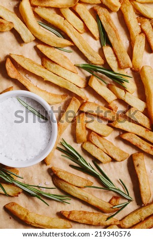 French fries with rosemary and salt on baking paper.