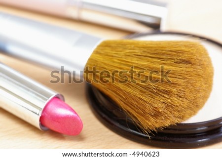 Close-up of make-up brush,  face powder and lipstick. Focus on brush, shallow DOF.
