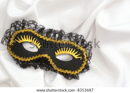 Black carnival mask with golden eyes on white background