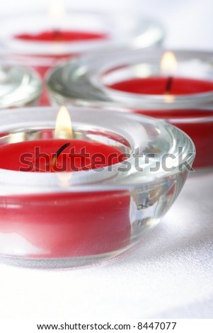 Red candles on white fabric background - focus on first candle, shallow DOF