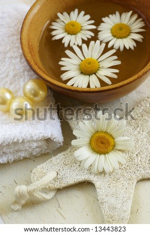 Massage sponge, towel, bath oil and marguerite in a bowl