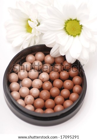 Face powder and flower on white background