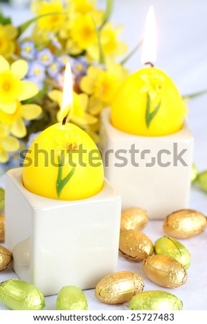 Easter still life with candle, flowers and chocolate eggs