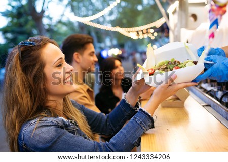 Shot of group of attractive young friends choosing and buying different types of fast food in eat market in the street.