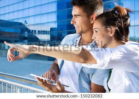 Outdoor portrait of one young couple using a digital tablet