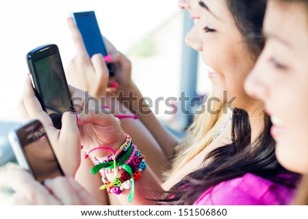 Three Girls Chatting With Their Smartphones At The Park