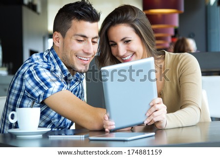 Portrait of young couple browsing internet with digital tablet in cafe