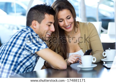 Portrait of young couple browsing internet with smartphonet in cafe