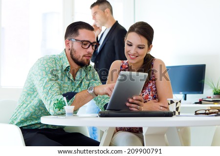 Portrait of casual executives working together at a meeting with digital tablet.