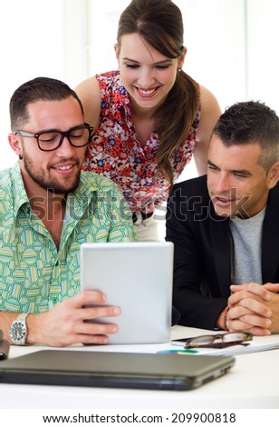 Portrait of casual executives working together at a meeting with digital tablet.