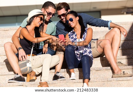 Outdoor portrait of group of friends having fun with smartphones.