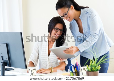 Portrait of two business woman working in office with digital tablet.