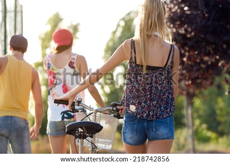 Outdoor portrait of group of friends with roller skates and bike riding in the park.
