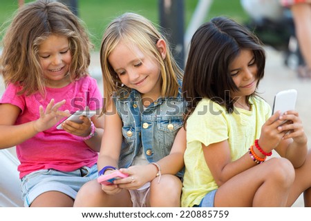 Portrait of group of childrens chatting with smart phones in the park.
