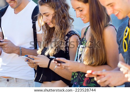 Portrait of group of students having fun with smartphones after class.