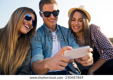 Portrait of group of friends taking a selfie with smartphone.