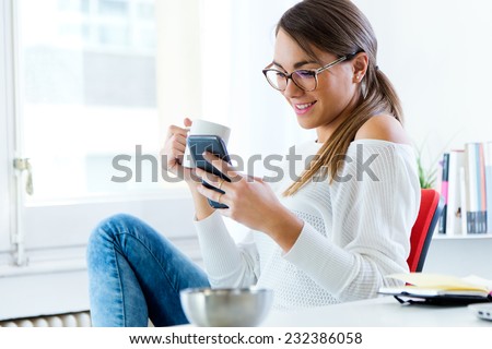 Portrait of pretty young woman using her mobile phone in the office.