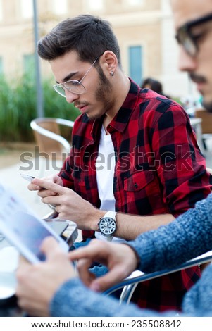 Outdoor portrait of two young entrepreneurs working at coffee shop.