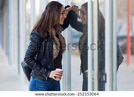 Outdoor portrait of young beautiful woman looking at the shop window.