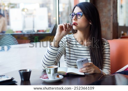 Portrait of young beautiful woman using her mobile phone in coffee.