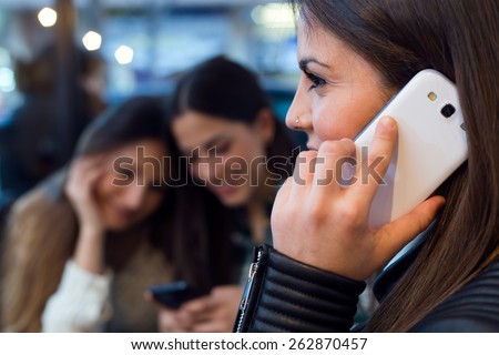 Portrait of three young woman using mobile phone at cafe shop.