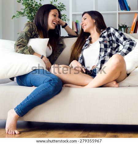 Portrait of two beautiful young woman staying on sofa at home.