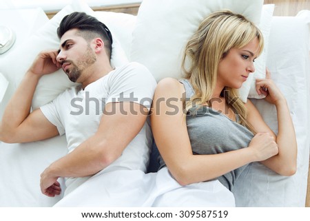 Portrait of upset couple lying back to back in bed